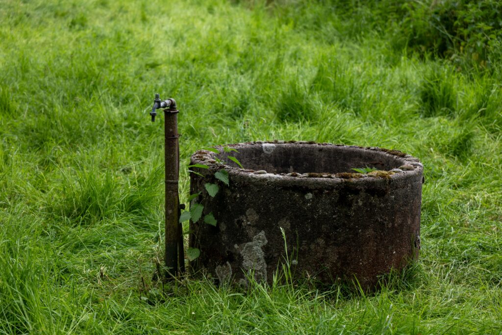 Old water well set in a lush green field